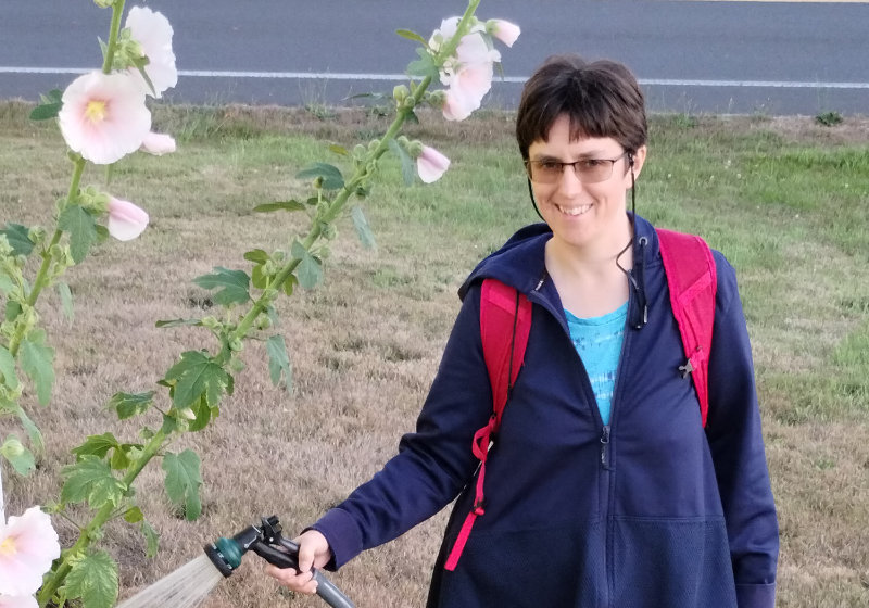 Linnea Huxford watering Hollyhock flowers