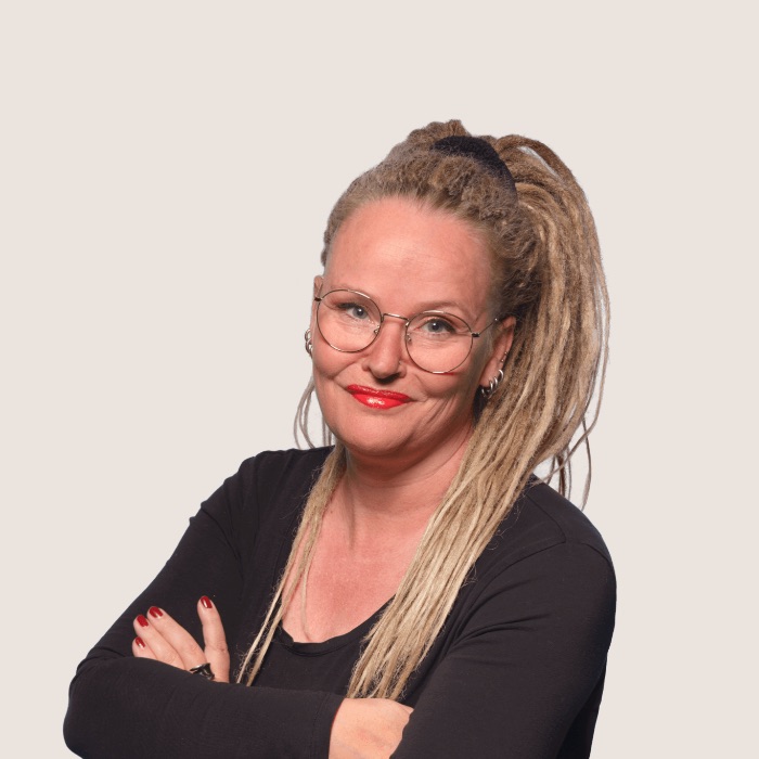 Portrait of Anne Bovelett. A smiling woman with long blonde hair in a luxuriant high ponytail and round glasses.